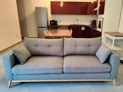 a couch in a living room with a kitchen at L'Atelier Cosy in Lézignan-Corbières