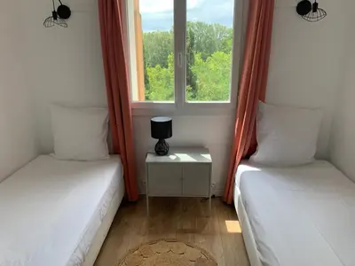 two beds in a room with two windows at Appartement familial avec parking privatif in Carcassonne