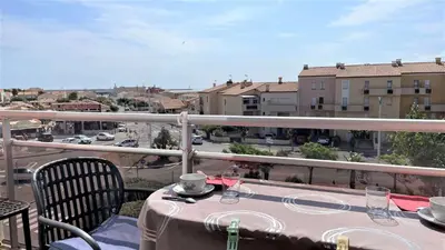 a table on a balcony with a view of a city at Appartement deux pièces Port La Nouvelle PN020-031 in Port-la-Nouvelle