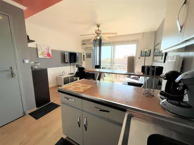 a kitchen with a counter top and a living room at Appartement deux pièces Port La Nouvelle PN020-031 in Port-la-Nouvelle