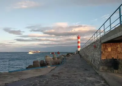 a lighthouse next to the ocean with a cruise ship at Studio 3 couchages PORT LA NOUVELLE PN040-004 in Port-la-Nouvelle