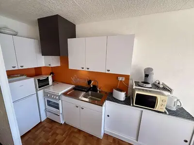 a small kitchen with white cabinets and a microwave at Studio 3 couchages PORT LA NOUVELLE PN040-004 in Port-la-Nouvelle