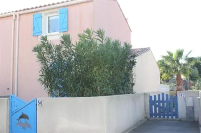 a house with a blue fence and a bush at Pavillon dans résidence avec piscine Grazel GA090-056 in Gruissan
