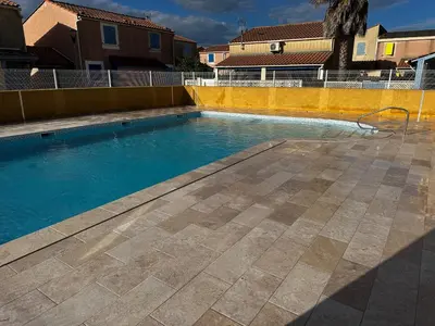 a swimming pool with blue water in a yard at Pavillon dans résidence avec piscine Grazel GA090-056 in Gruissan
