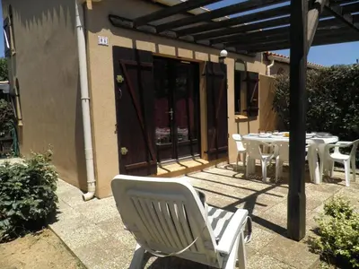 an outdoor patio with a table and chairs and a pergola at Maison 2 pièces cabine - Gruissan GN020-084 in Gruissan
