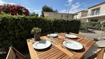 a wooden table with plates and wine glasses on it at Appartement 2 pièces climatisé proche du port GN190-015 in Gruissan