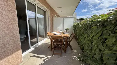 a wooden table and chairs on a patio at Appartement 2 pièces climatisé proche du port GN190-015 in Gruissan