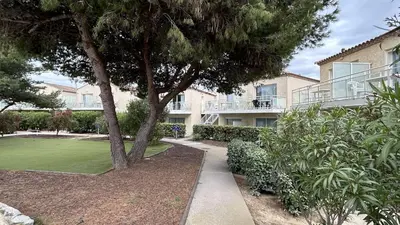 a tree in front of a building with a yard at Appartement 2 pièces climatisé proche du port GN190-015 in Gruissan