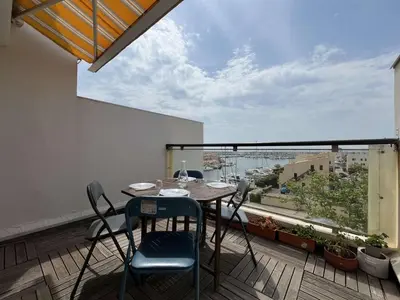 a patio with a table and chairs on a balcony at Appartement dernier étage avec terrasse vue port GN400-028 in Gruissan