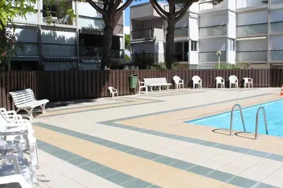 a patio with chairs and a pool in front of a building at Appartement dernier étage avec terrasse vue port GN400-028 in Gruissan