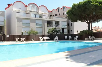 a swimming pool with chairs and a building at Appartement dernier étage avec terrasse vue port GN400-028 in Gruissan
