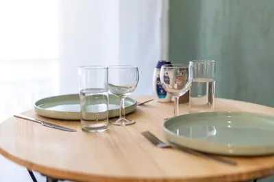 a wooden table with plates and glasses on it at Le Jasmin - Netflix Inclus in Narbonne