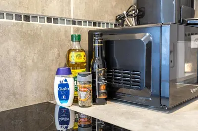 a counter with bottles of alcohol and spices next to a microwave at Le Jasmin - Netflix Inclus in Narbonne