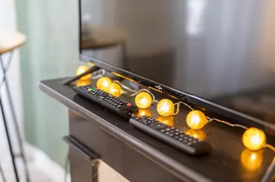 two remote controls sitting on a table with lights at Le Jasmin - Netflix Inclus in Narbonne