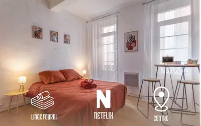 a bedroom with a bed and two chairs and a table at L'Ocre - Netflix Inclus in Narbonne