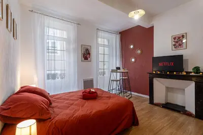 a bedroom with a red bed and a fireplace at L'Ocre - Netflix Inclus in Narbonne