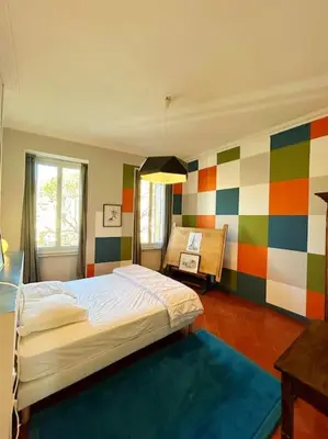 a bedroom with a bed and a colorful wall at La Maison Cardau in Névian