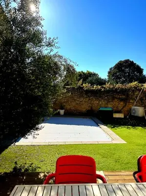 two red chairs sitting on a deck in a yard at La Maison Cardau in Névian