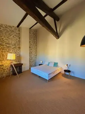 a bedroom with a bed and a stone wall at La Maison Cardau in Névian