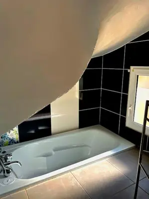 a bath tub in a bathroom with black tiles at La Maison Cardau in Névian