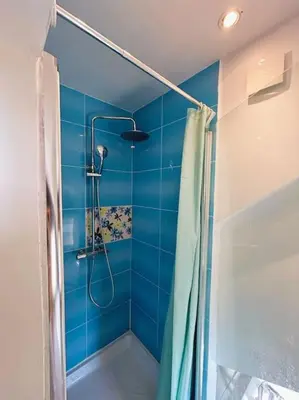 a bathroom with a shower with a blue wall at La Maison Cardau in Névian