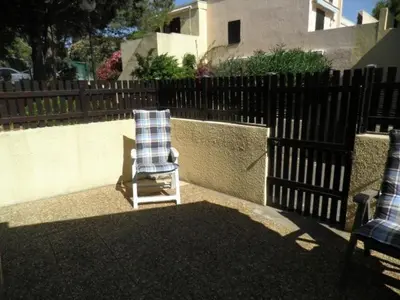 a chair sitting in a yard next to a fence at Appartement avec parking privé proche de la plage GN250-089 in Gruissan