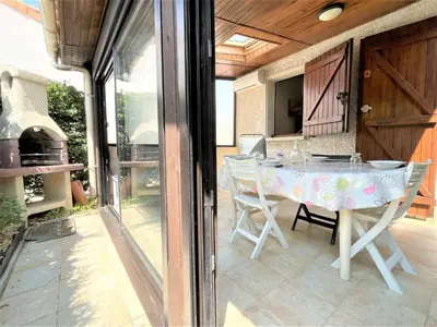a patio with a table and chairs and a grill at Petit pavillon climatisé avec parking privé Grazel GN490-055 in Gruissan