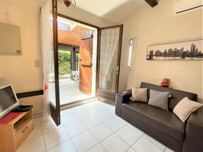 a living room with a black couch and a tv at Petit pavillon climatisé avec parking privé Grazel GN490-055 in Gruissan