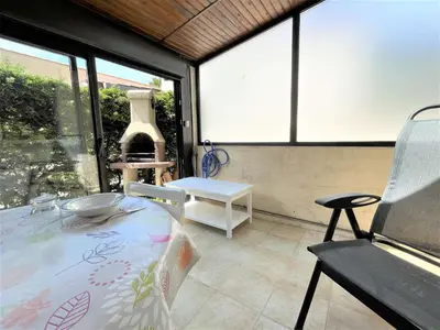 a room with a table and a chair and windows at Petit pavillon climatisé avec parking privé Grazel GN490-055 in Gruissan
