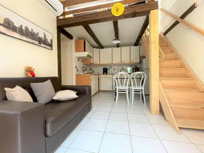 a living room with a couch and a kitchen at Petit pavillon climatisé avec parking privé Grazel GN490-055 in Gruissan