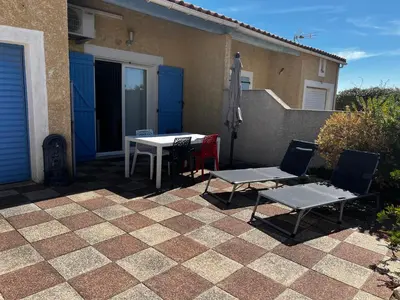 a patio with a table and chairs and an umbrella at Maison de vacances à la mer in Port-la-Nouvelle