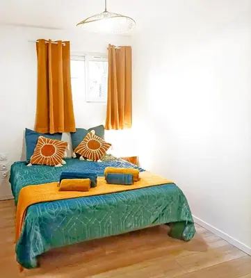 a bedroom with a large bed with orange curtains at l'Entre Nous, jacuzzi privé et piscine à Carcassonne in Carcassonne