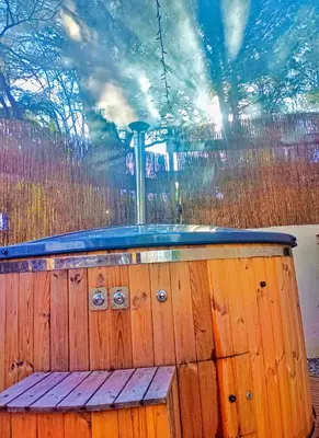 a jacuzzi in a wooden tub with a fence at l'Entre Nous, jacuzzi privé et piscine à Carcassonne in Carcassonne
