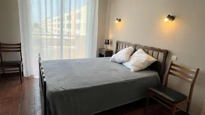 a bed in a bedroom with a window and a chair at Appartement 3 pièces PORT LA NOUVELLE PN050-015 in Port-la-Nouvelle