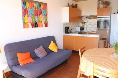 a living room with a blue couch and a kitchen at Appartement 3 pièces PORT LA NOUVELLE PN050-015 in Port-la-Nouvelle