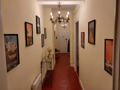 a hallway with a chandelier and pictures on the walls at Appartement vue panoramique in Carcassonne