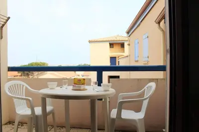 a white table and chairs on a balcony at Appartement Studio mezzanine PORT LA NOUVELLE PN290-103 in Port-la-Nouvelle