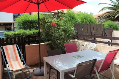 a table and chairs with a red umbrella on a patio at APPARTEMENT 3 pieces PORT LA NOUVELLE PN340-126 in Port-la-Nouvelle