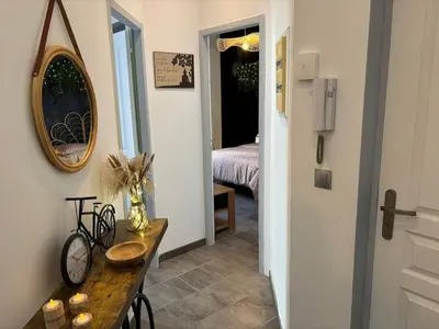 a hallway with a table and a room with a bed at Cocon Bohème Proche Gare in Narbonne