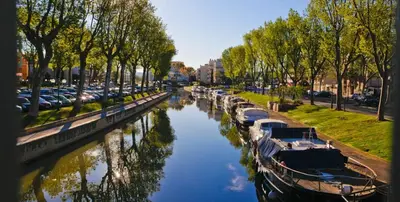 a group of boats docked on a river with trees at Cocon Bohème Proche Gare in Narbonne