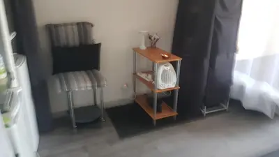a bedroom with a night stand with a fan and a chair at Les Vergers in Narbonne