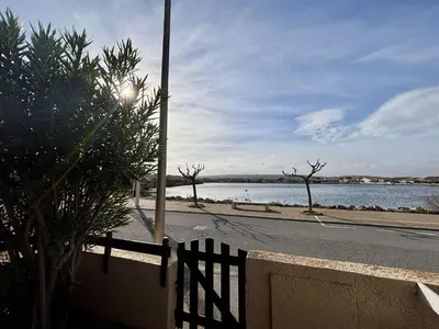 a fence next to a road next to a body of water at Maison deux pièces cabine PORT LA NOUVELLE PN370-026 in Port-la-Nouvelle
