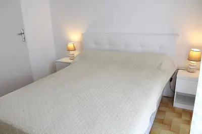 a bedroom with a white bed with two lamps on night stands at Appartement 2 pièces PORT LA NOUVELLE PN440-024 in Port-la-Nouvelle