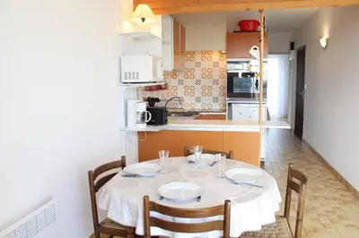 a dining room table with chairs and a kitchen at Appartement 2 pièces PORT LA NOUVELLE PN440-024 in Port-la-Nouvelle