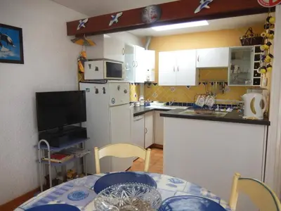 a kitchen with a table and a white refrigerator at Maison 3 pièces PORT LA NOUVELLE PN500-005 in Port-la-Nouvelle