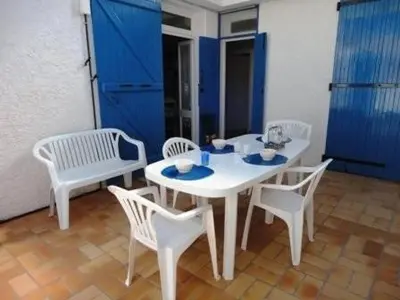 a white table and chairs and a blue door at Maison 3 pièces PORT LA NOUVELLE PN500-005 in Port-la-Nouvelle