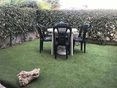a table and chairs on the grass with a log at Appartement 2 pièces PORT LA NOUVELLE PN520-031 in Port-la-Nouvelle