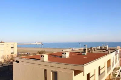 a view of a building with the ocean in the background at Appartement 2 pièces PORT LA NOUVELLE PN590-033 in Port-la-Nouvelle