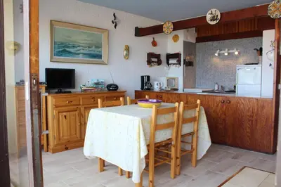 a kitchen with a table with chairs and a refrigerator at Appartement 2 pièces PORT LA NOUVELLE PN590-033 in Port-la-Nouvelle