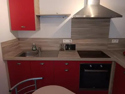 a small kitchen with red cabinets and a sink at Studio in Lézignan-Corbières